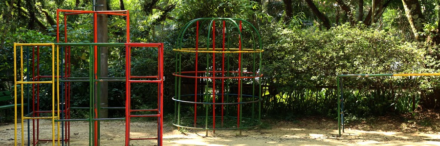Dois brinquedos em parques feitos de ferro coloridos, verde, amarelo, vermelho